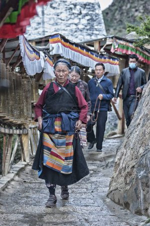 Foto de SHIGATSE, TIBET, CHINA - 22 AGOSTO 2018: Peregrinos tibetanos no identificados y ruedas de oración a lo largo de una ruta de peregrinos en el Monasterio de Tashilhunpo - Shigatse, Tibet - Imagen libre de derechos