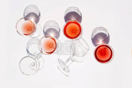 Téléchargez les photos : Un ensemble de verres avec du vin sur fond blanc. Tendance contrastée des ombres - en image libre de droit