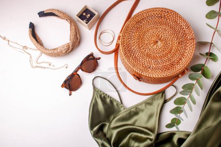 Téléchargez les photos : Robe verte pour femme, sac en osier et décorations de bijoux sur fond blanc. Style plat laïc - en image libre de droit
