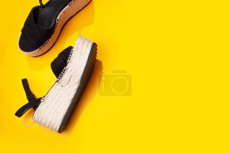Photo for Sandals espadrilles with straw soles on a yellow background. Flat lay style - Royalty Free Image