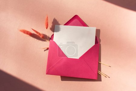 Photo for A blank sheet for writing in a crimson envelope with contrasting shadows. Valentine's Day. Flat lay style - Royalty Free Image