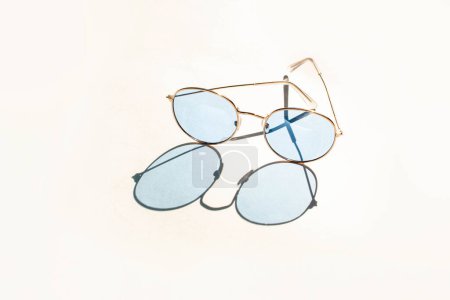 Foto de Gafas de sol con estilo azul sobre fondo blanco. Sombras contrastantes. Concepto gafas de moda de verano - Imagen libre de derechos