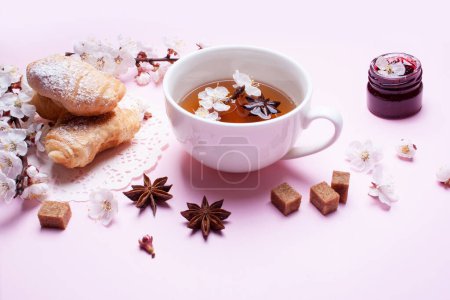 Téléchargez les photos : Tasse de thé, croissants et branches florissantes de printemps sur fond rose - en image libre de droit