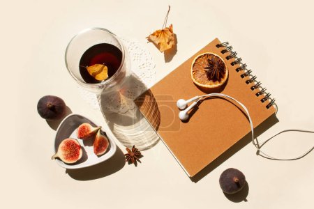 Photo for Glass of coffee, figs, notebook and autumn leaves with contrasting shadows on a white table - Royalty Free Image