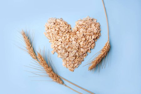 Photo for Heart-shaped oatmeal and wheat on a blue background. Flat Lay Style - Royalty Free Image