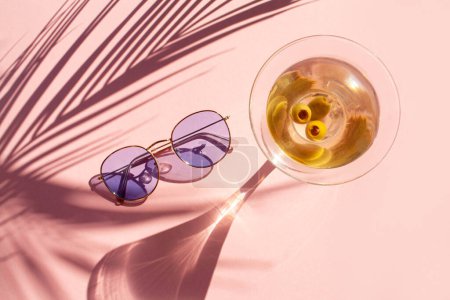 Foto de Vidrio Martini, gafas de sol y sombra de hoja de palma sobre fondo rosa - Imagen libre de derechos