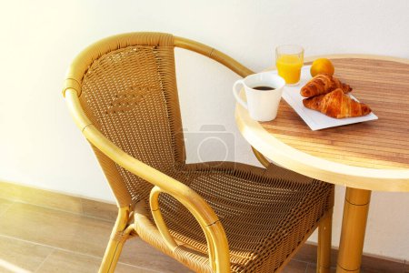 Photo for Morning breakfast on the summer terrace. Lamella chair, table, coffee and croissants - Royalty Free Image