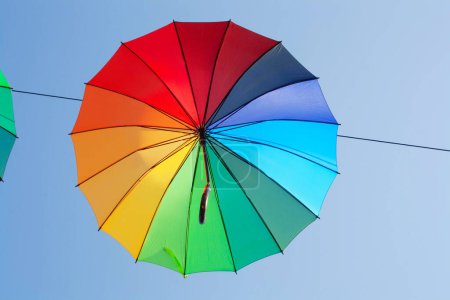 Téléchargez les photos : Un parapluie multicolore contre le ciel bleu. Concept d'automne, pluie - en image libre de droit