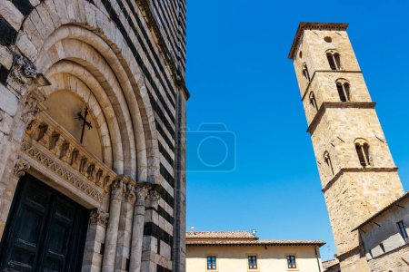 Facade of the Baptistery of Saint John and the clock tower of the cathedral in Volterra, Tuscany, Italy, Europe