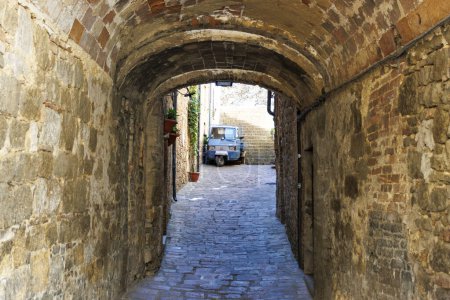 Old center of Volterra with a narrow arched street and a Piaggio Ape, Tuscany, Italy, Europe