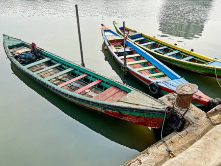Photo for Three colorful wooden boats are tied up at a jetty in the harbor of Jakarta. - Royalty Free Image