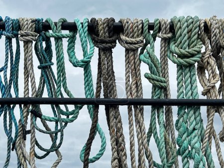 Foto de Un surtido de cuerdas atadas a la barandilla de un barco están listas para su uso en un barco pesquero. - Imagen libre de derechos
