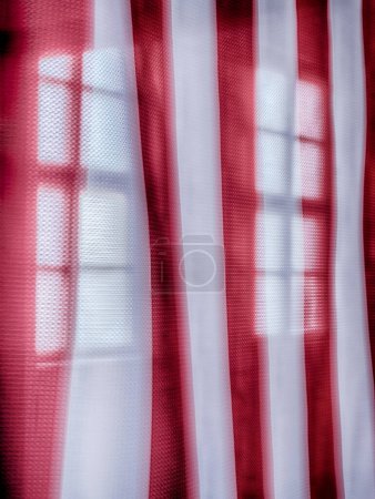 Photo for MAUTHAUSEN, AUSTRIA - DECEMBER 4, 2022: A portion of the American flag inside one of the buildings at the Mauthausen concentration camp commemmorates the liberation of the camp. A window can be seen through the red and white stripes of the flag. - Royalty Free Image