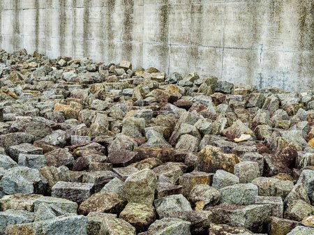 Photo for MAUTHAUSEN, AUSTRIA - DECEMBER 4, 2022: A pile of heavy stones heaped up outside a concrete wall memorializes the slave labor from the quarry at the Mauthausen concentration camp in Austria. - Royalty Free Image