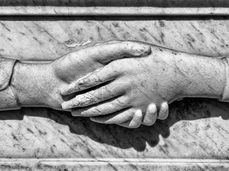 Téléchargez les photos : Deux mains, taillées dans la pierre, sont maintenues à jamais sur une pierre tombale au cimetière du Père Lachaise à Paris. - en image libre de droit