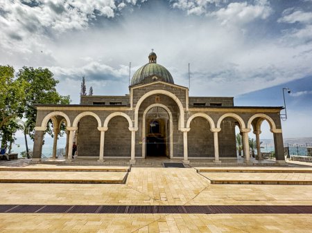 The front entrance to the Church Of The Beatitudes as seen over the main courtyard with mountains and clouds behind.