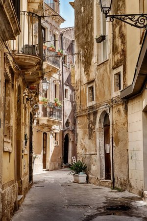 A narrow street on the island of Ortygia in Siricusa, Sicily is deep in shadow.