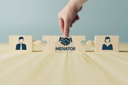 Photo for The hand holds wooden wooden blocks with icons of a woman and a man and shaking hands in the act of consent. The concept of divorce, agreement, mediation, the role of the mediator. - Royalty Free Image