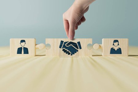 Photo for The hand holds wooden wooden blocks with icons of a woman and a man and shaking hands in the act of consent. The concept of divorce, agreement, mediation, the role of the mediator. - Royalty Free Image
