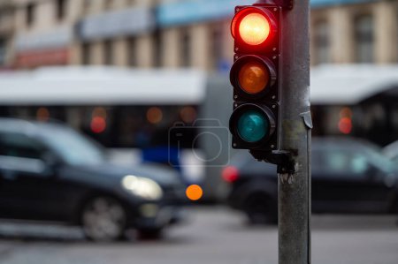 Photo for Blurred view of city traffic with traffic lights, in the foreground a semaphore with a red light - Royalty Free Image