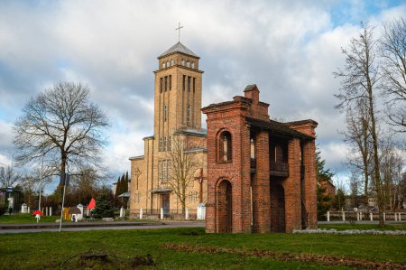 Téléchargez les photos : Old Catholic Church and red brick gates in city Akniste, Latvia. Aknistes visual identity symbol. - en image libre de droit