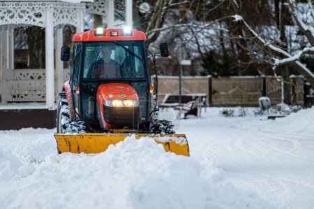 Foto de Jurmala, Letonia, 25 de diciembre de 2021: Un tractor quitanieves limpia la zona del parque. Servicio municipal limpieza acera de nieve. - Imagen libre de derechos