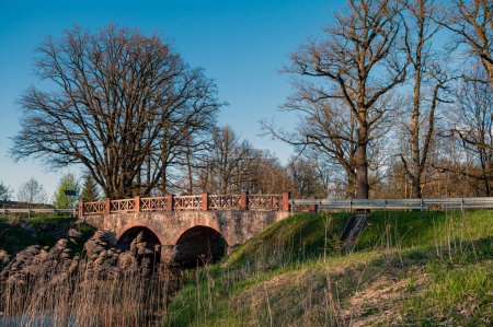 Old stone bridge over the river in the park. Spring landscape.