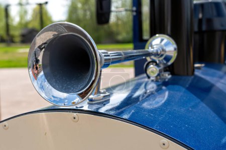 Primer plano del cuerno de señal vintage de acero en un coche azul en el parque, enfoque selectivo