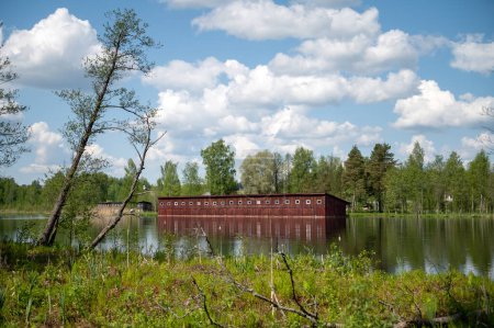 Téléchargez les photos : Hangar à bateaux en bois sur la rive du lac avec réflexion dans l'eau. Aluksne, Lettonie - en image libre de droit