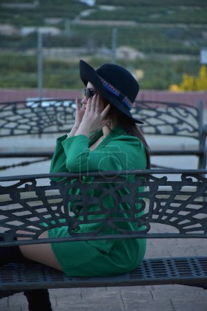 Téléchargez les photos : Belle jeune femme dans un chapeau et robe noire posant dans le parc - en image libre de droit