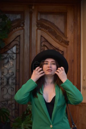 Téléchargez les photos : Belle fille dans une robe verte sur un fond d'une vieille maison en bois - en image libre de droit
