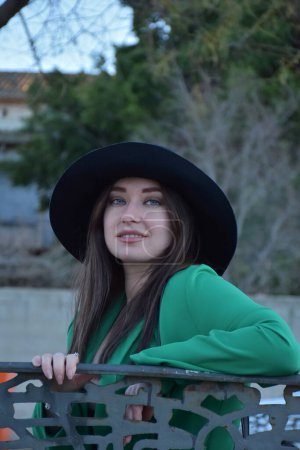 Foto de Hermosa joven con un sombrero y vestido negro posando en el parque - Imagen libre de derechos