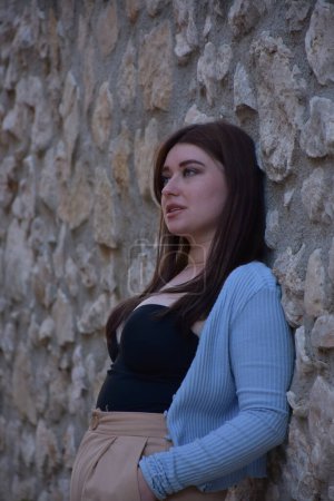 Téléchargez les photos : Jeune belle fille dans une robe noire sur un fond de mur de briques - en image libre de droit