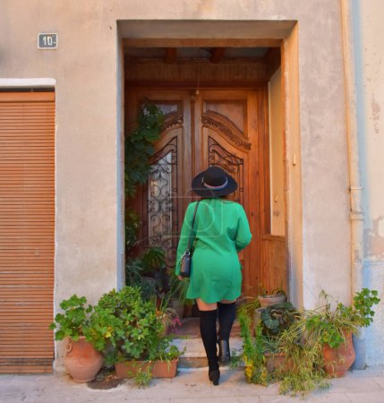 Téléchargez les photos : Jeune femme avec chapeau à l'entrée d'une vieille maison - en image libre de droit