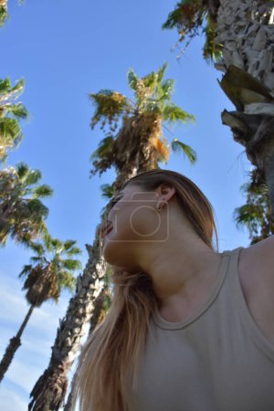 Foto de Beautiful young woman in park with palm trees - Imagen libre de derechos