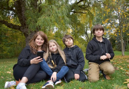 Photo for Family of four with a tablet in the autumn park. - Royalty Free Image