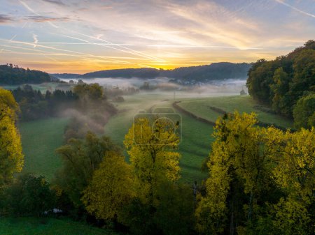 Photo for Aerial drone Sunrise view Above autumn colored forest and Valleys in Luxembourg, covered in morning fog. 4k drone footage - Royalty Free Image