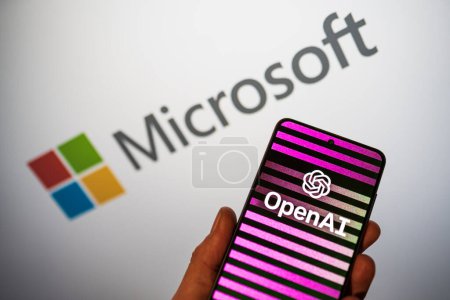 Photo for OpenAI logo on phone in a hand and blurred Microsoft logo on the background. Bing integrates ChatGPT AI chatbot to the search engine. Warsaw, Poland - February 15, 2023. - Royalty Free Image