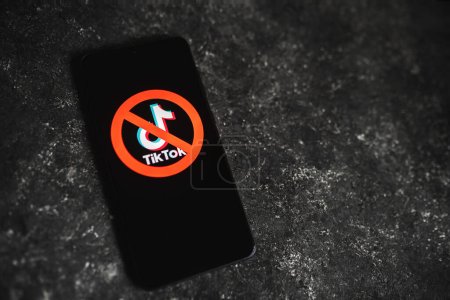 Téléchargez les photos : Logo de l'application TikTok rayé avec panneau rouge Ban affiché sur l'écran du téléphone. Tik Tok interdit dans le concept américain. Fond en béton foncé avec espace de copie. Swansea, Royaume-Uni - 15 février 2023. - en image libre de droit