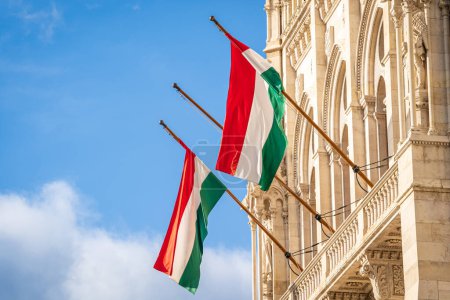 Banderas nacionales de Hungría. Dos banderas húngaras en asta de bandera colgando en un edificio contra el cielo azul.