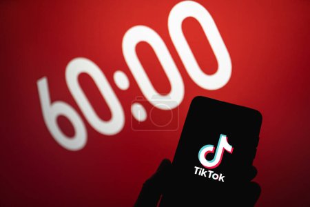 Téléchargez les photos : TikTok fixe un délai d'une heure pour les utilisateurs de moins de 18 ans. Tik Tok app logo sur le téléphone à côté de 60 minutes de texte sur l'arrière-plan. Swansea, Royaume-Uni - 1er mars 2023. - en image libre de droit