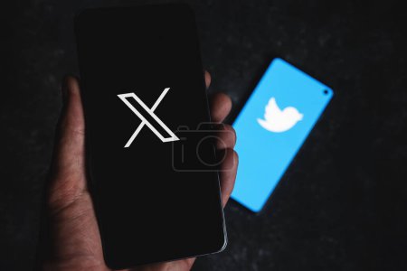 Foto de Nuevo logotipo de Twitter X en la pantalla del smartphone y viejo icono azul con pájaro en el fondo. Twitter 2023 Rebranding. Swansea, Reino Unido - 26 de julio de 2023 - Imagen libre de derechos