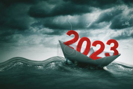 Close up of 2023 number with a paper ship floating on the sea with storm sky background