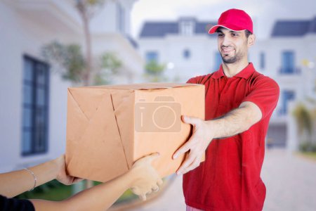Photo for Close up of young woman hands accepting a package from a courier while standing in front of home with residential background - Royalty Free Image