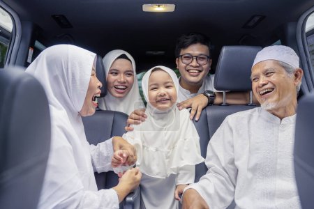 Foto de Feliz familia musulmana de tres generaciones sentada en dos filas de asientos de pasajeros en el coche - Imagen libre de derechos