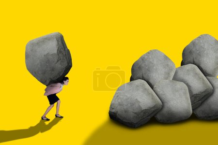 Foto de Empresaria sosteniendo una gran roca pesada aislada sobre fondo amarillo - Imagen libre de derechos