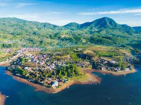 Schöne Landschaftsaufnahme einer kleinen Stadt am See mit Bergkulisse auf Bali, Indonesien
