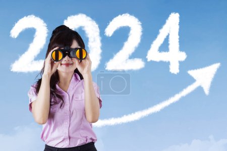 Photo for Female entrepreneur using binoculars with the 2024 new year numbers and upward arrow on the background - Royalty Free Image