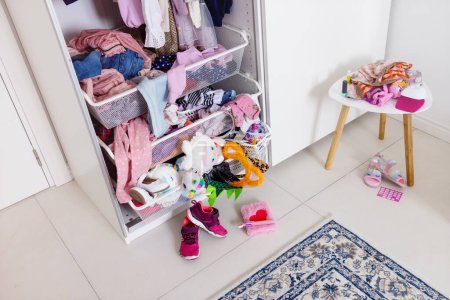 Clutter in a modern little girls room. close-up of a large white closet, where things are in a mess, heap and dirt. The concept of organizing space, optimizing things, recycling, parenting