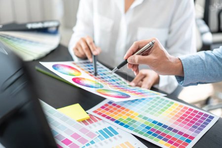 Two creative graphic designer team working on color selection and drawing on graphic tablet, Color swatch samples chart for selection coloring in inspiration to creativity at workplace.